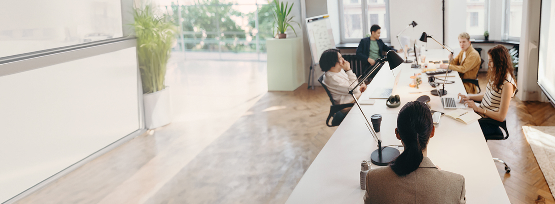 Mehrere Kollegen sitzen in einem Meeting an einem Tisch und reden miteinander